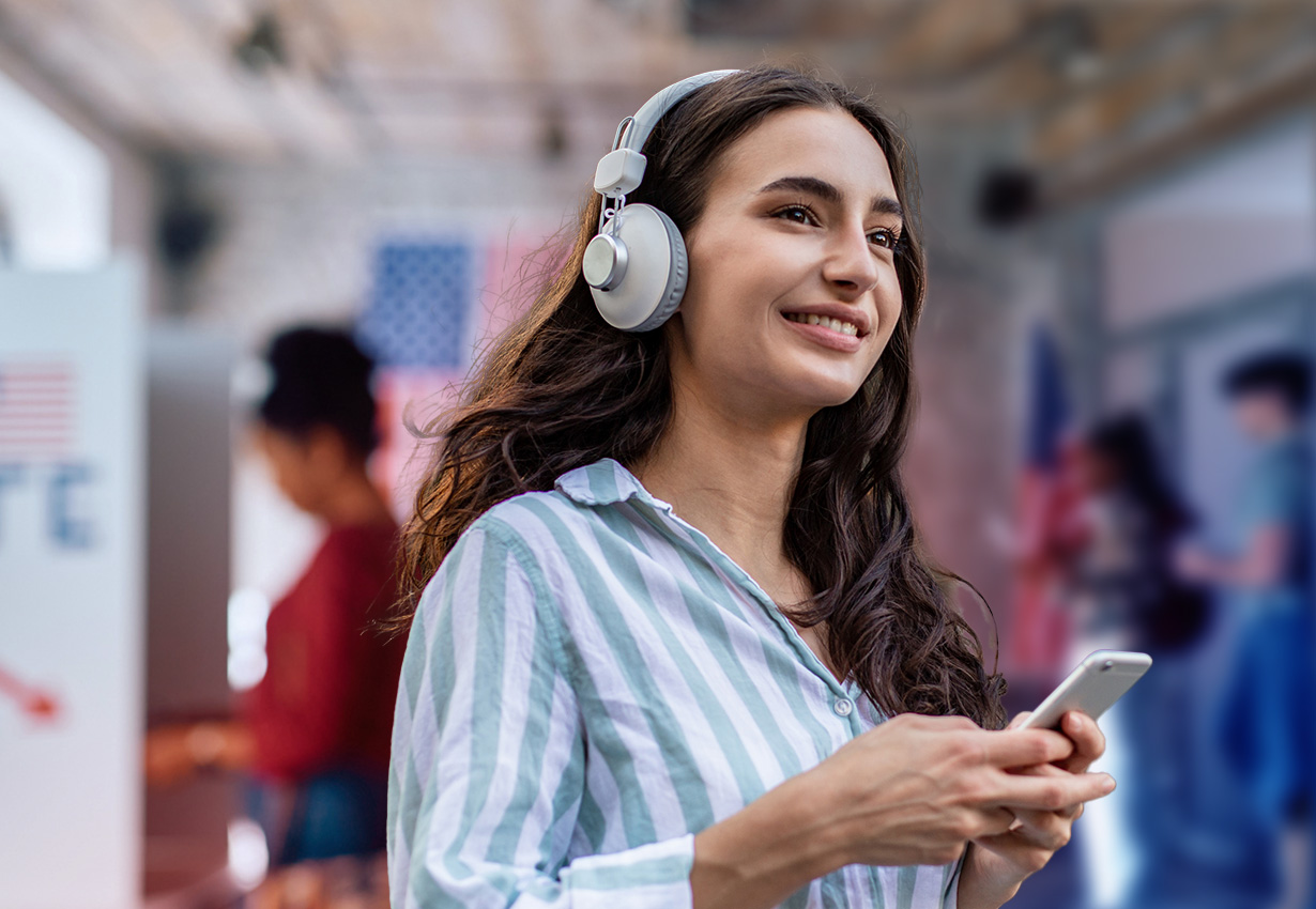 Young voter listens to a podcast on her phone while others vote at the ballot box.